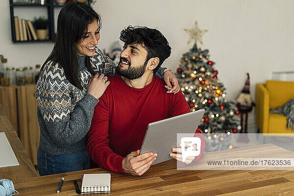 Woman with boyfriend holding tablet PC at home
