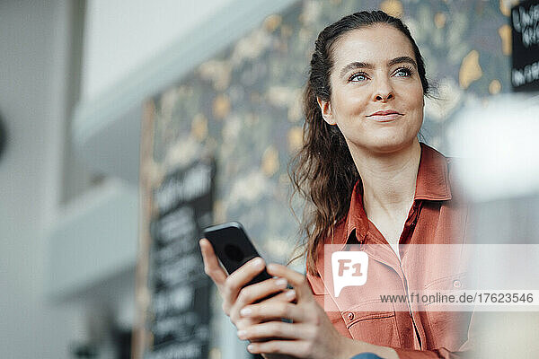 Lächelnde Frau mit Smartphone im Café