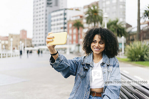 Smiling woman taking selfie on mobile phone in city