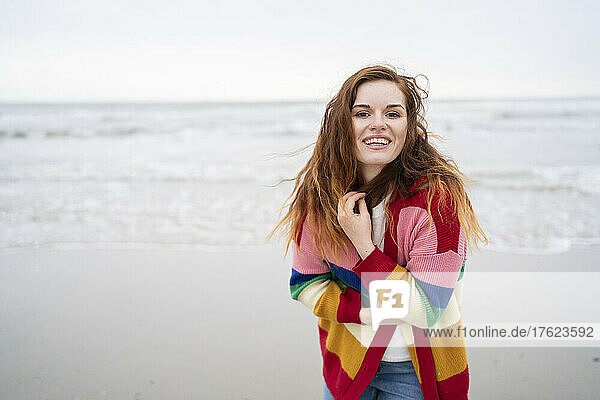 Cheerful redhead woman in cardigan sweater enjoying at beach