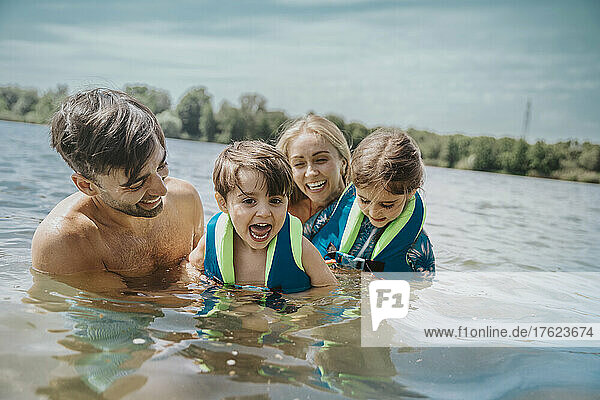 Cheerful parents swimming with children in lake