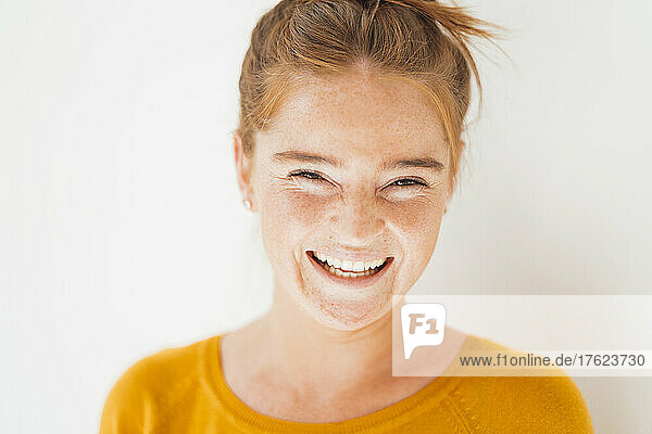 Young woman laughing in front of white background