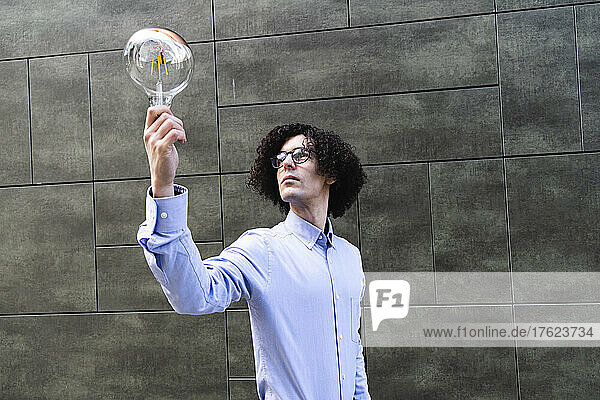 Man holding bulb standing in front of wall