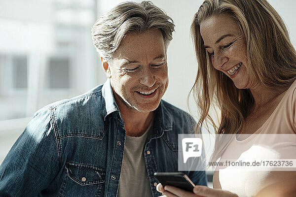 Smiling woman sharing mobile phone with man