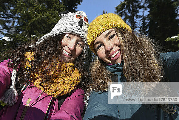 Smiling women with long hair wearing knit hat in winter on sunny day