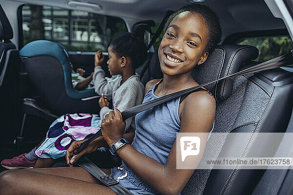Smiling girl sitting with sister in car