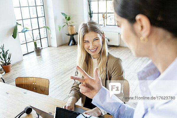Happy blond businesswoman discussing with colleague in home office