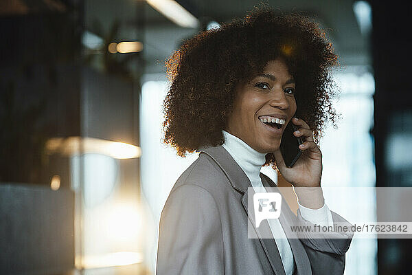 Happy businesswoman talking on smart phone in office