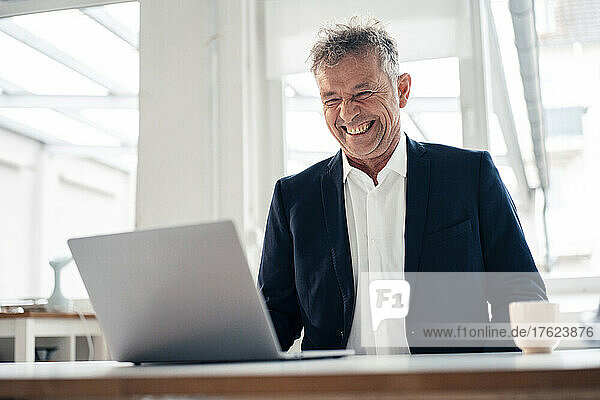 Happy businessman using laptop in office