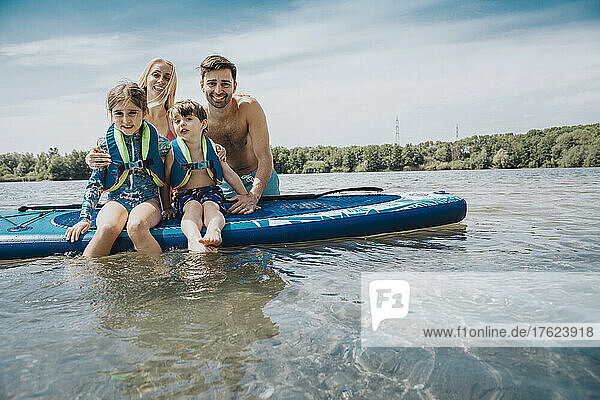 Smiling family with paddleboard in lake on weekend