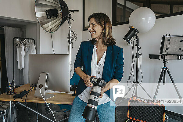Smiling photographer holding camera in studio