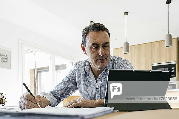 Musician looking at tablet PC sitting at home