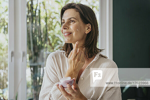 Woman using facial cream at home