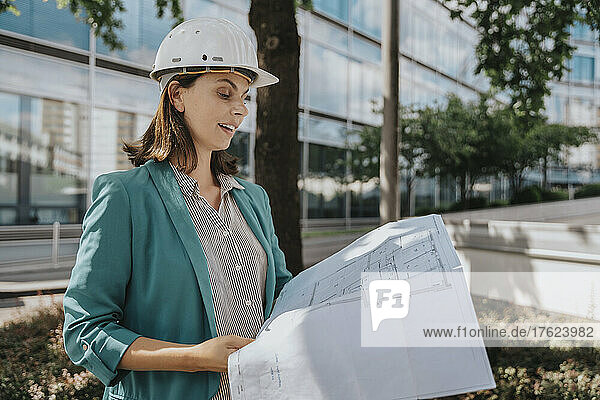 Architect in smart casuals examining construction plan