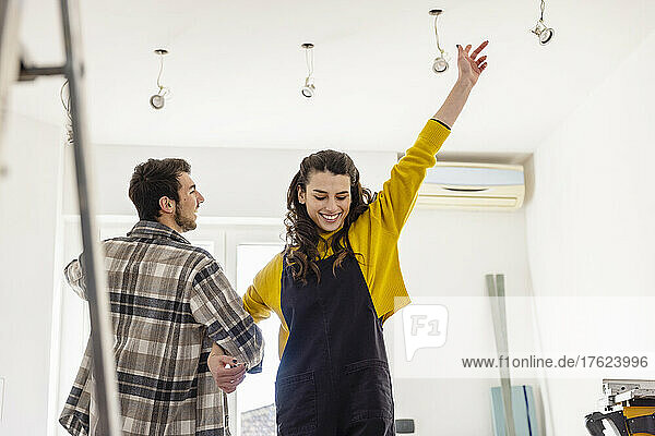 Glückliche Frau tanzt mit ihrem Freund im Wohnzimmer