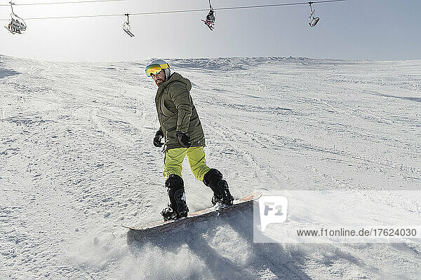 Young man snowboarding on snowcapped mountain