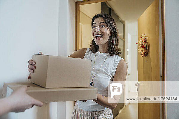 Surprise woman receiving packages from delivery person at door