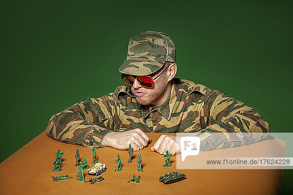 Military soldier with army figurines against green background