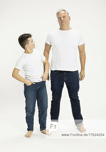 Boy with father standing against white background at studio