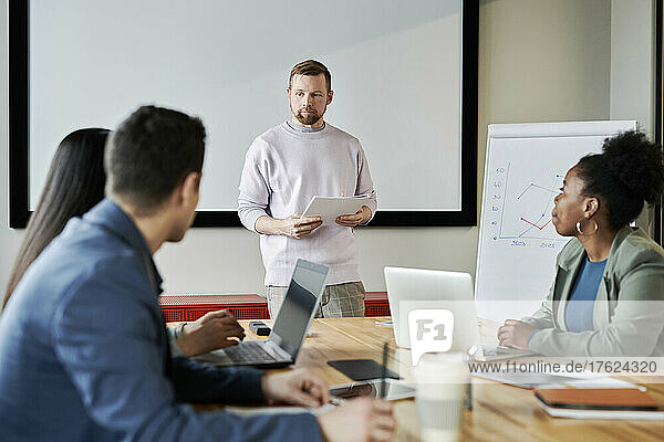 Businessman with document starting presentation with colleagues in meeting room