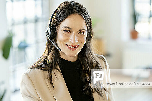 Lächelnde Geschäftsfrau mit Headset im Heimbüro
