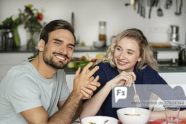 Smiling blond woman looking at boyfriend sitting at table