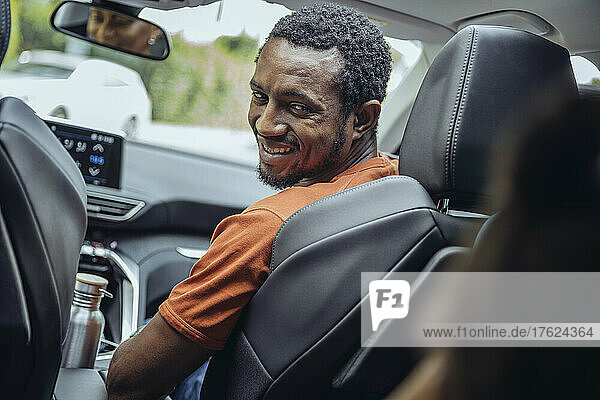Smiling man looking over shoulder in car