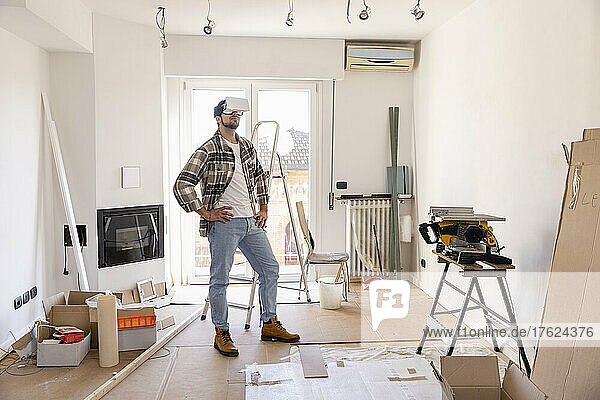 Junger Mann mit VR-Brille blickt auf Hausrenovierung