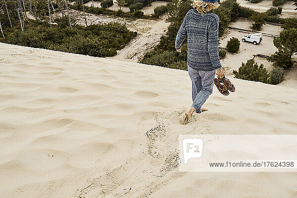 Tourist mit Schuhen läuft im Urlaub auf Sanddüne