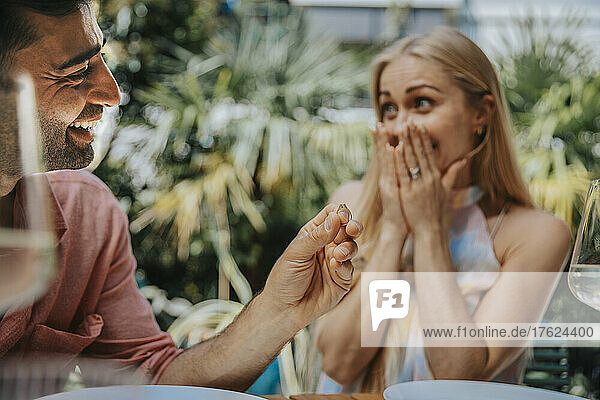 Happy man surprising woman with ring