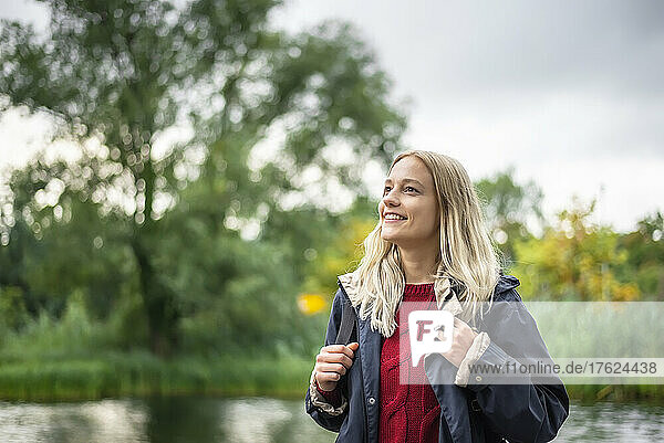 Happy blond woman standing in public park