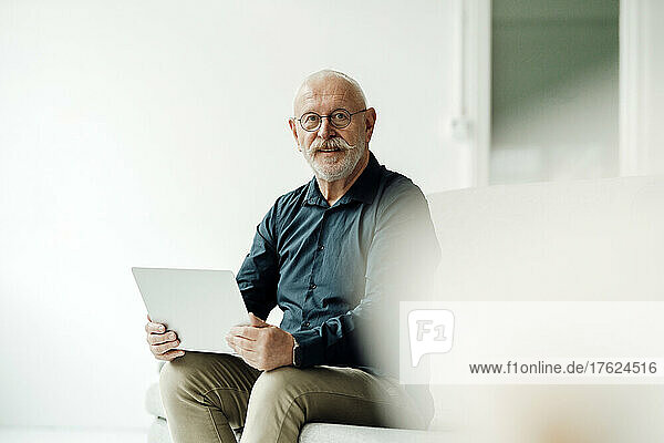 Senior businessman sitting with laptop in office