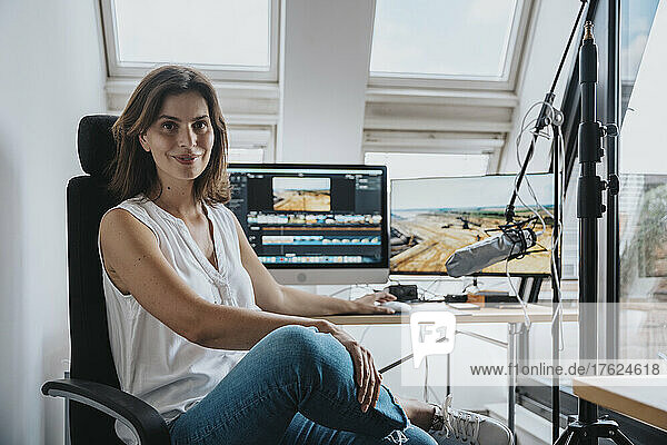 Fotograf sitzt auf einem Stuhl vor einem Desktop-PC im Studio
