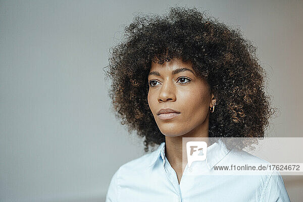 Contemplative businesswoman with curly hair in office