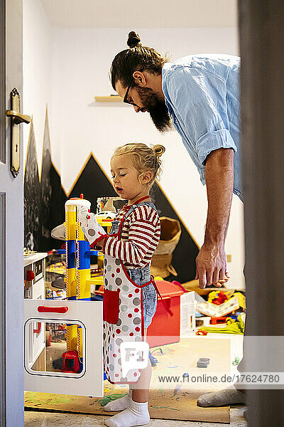 Father and son playing with toy kitchen at home