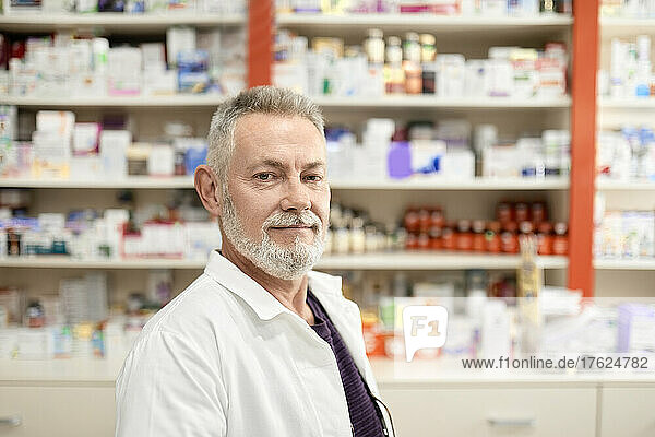 Confident pharmacist standing at pharmacy store