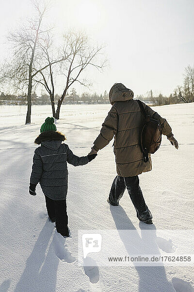 Mother and son holding hands and walking on snow