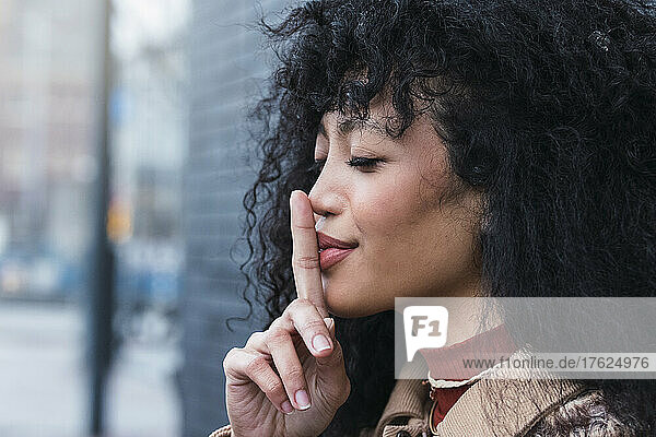 Beautiful woman with eyes closed gesturing finger on lips