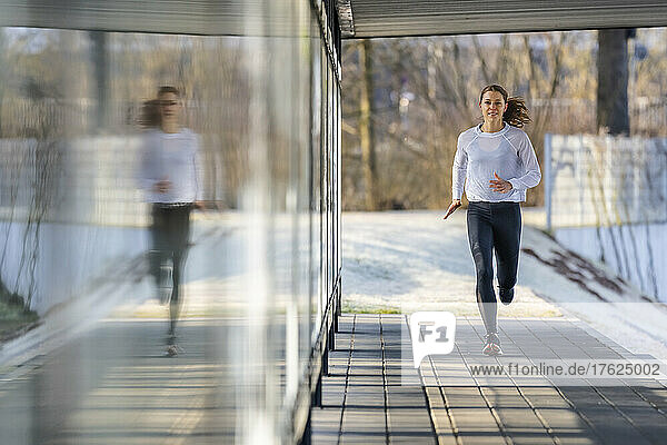 Woman in sports clothing jogging on footpath