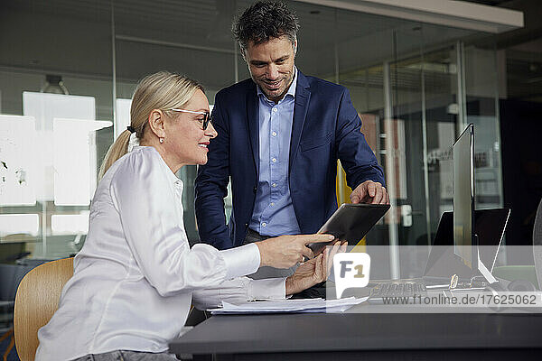 Geschäftsfrau teilt Tablet-PC mit Kollegen im Büro