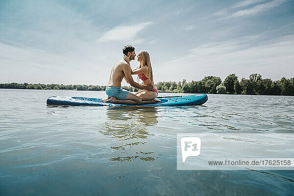 Couple on paddleboard floating over lake