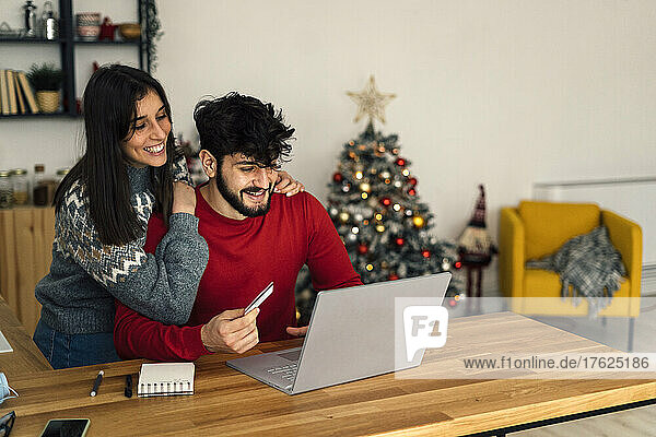 Happy couple doing online shopping through laptop at home