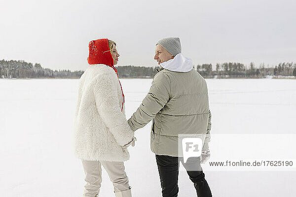 Couple holding hands standing on snow in winter