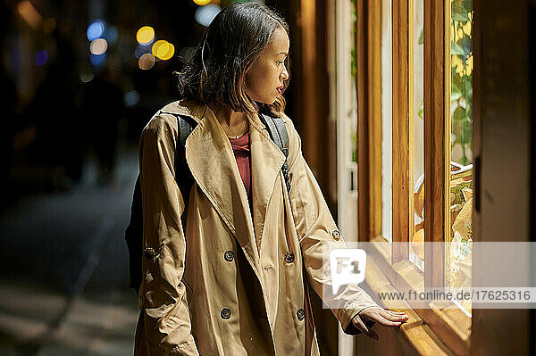 Junge Frau blickt auf die Schaufensterauslage eines Ladens