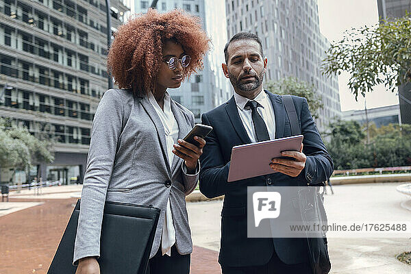 Businessman showing female colleague something on digital tablet
