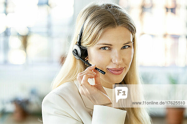Smiling young businesswoman with headset at home office