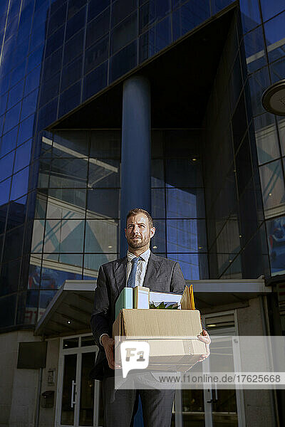 Businessman with box of personal belongings in city