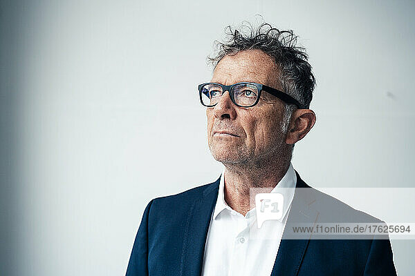 Thoughtful businessman in suit against white background