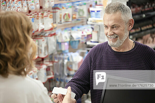 Happy customer receiving medicine from pharmacist at checkout counter