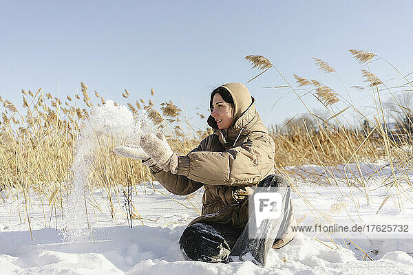 Woman playing with snow at field